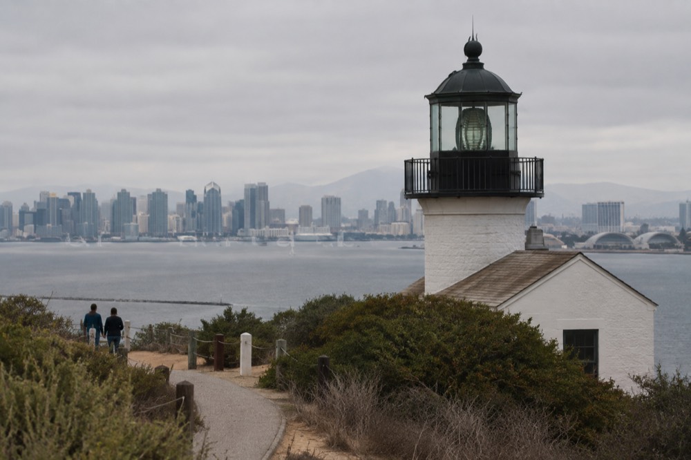 A coastal overlook with a historic lighthouse above calm ocean water