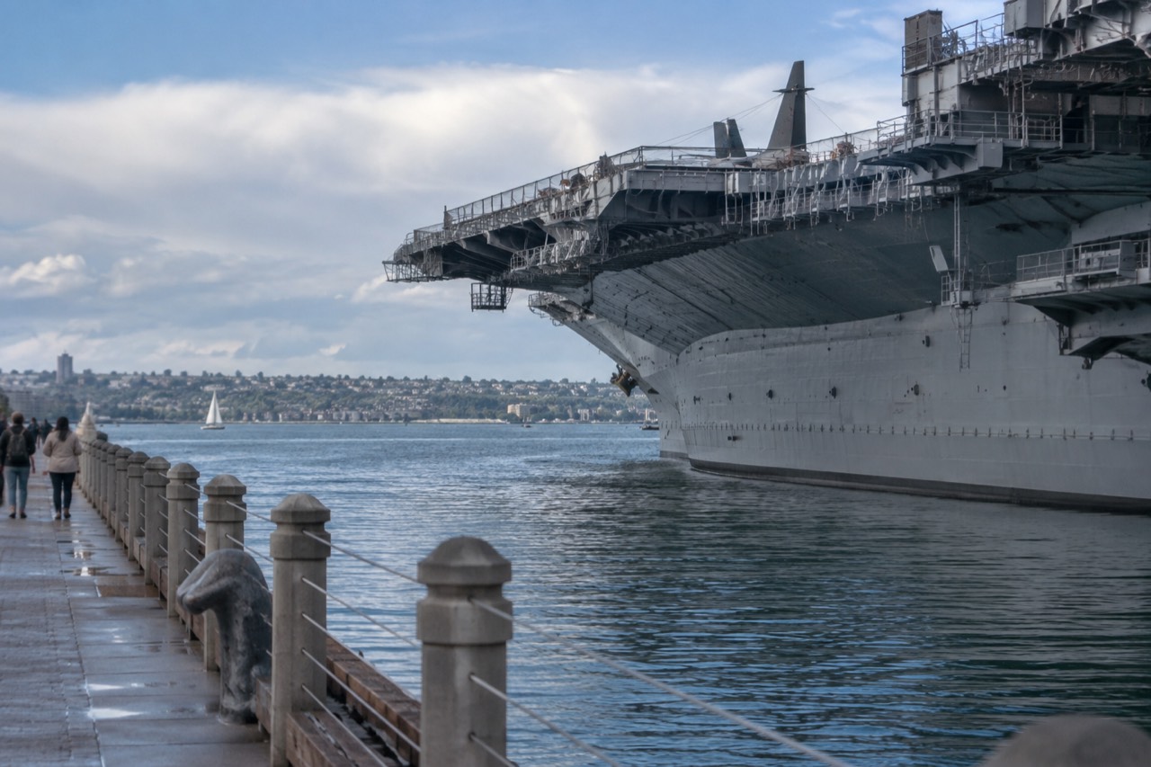A calm San Diego bay with a historic aircraft carrier ship museum along the waterfront